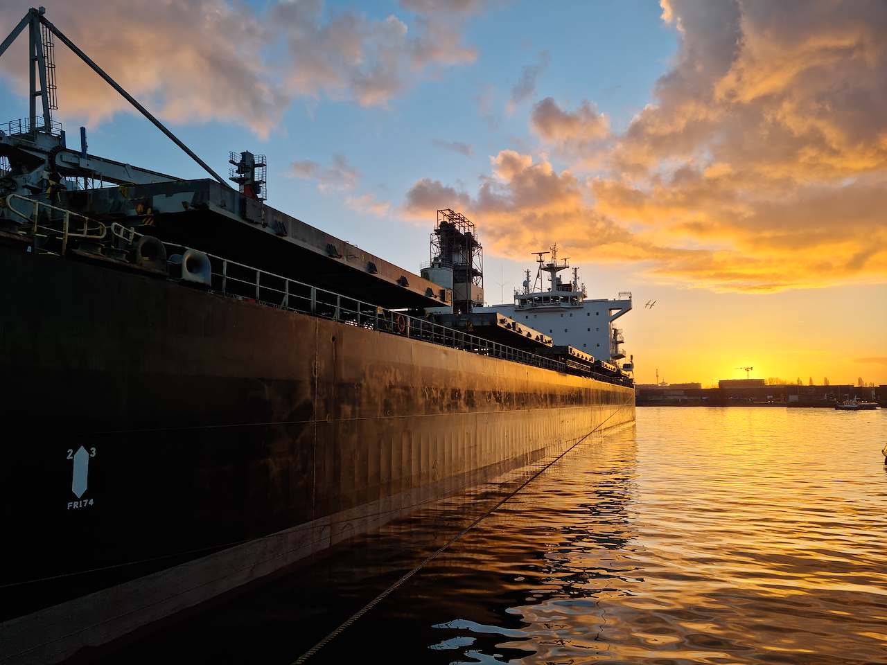 Vrachtschip aan de kade bij zonsopkomst
